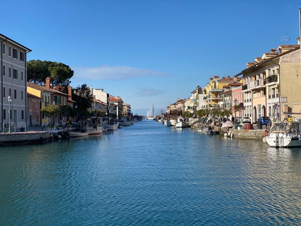 Canale a Grado con barche ormeggiate tra file di case chiare
